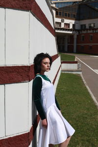 Side view of young woman with eyes closed standing by wall during sunny day