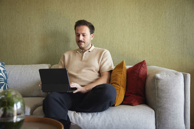 Man using laptop on sofa in living room