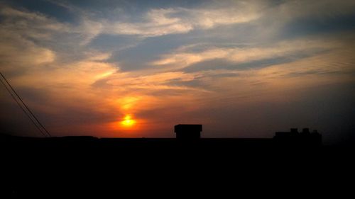 Silhouette house against sky during sunset