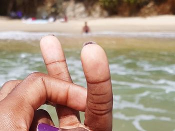 Close-up of woman fingers against sea