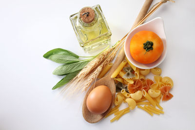 Dry pasta with tomatoes and herbs on white background, top view