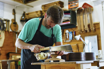 Luthier cutting fretboard on workbench in workshop