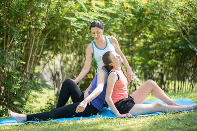 Yoga instructor instructing to women doing yoga at park