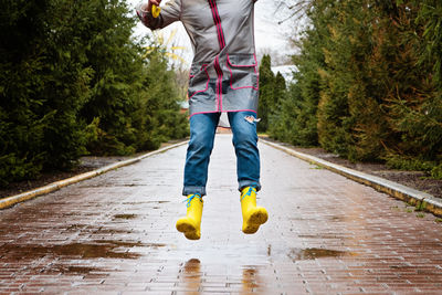 Jumping in puddle. female legs in yellow rubber boots jumping on the puddle. carefree young woman