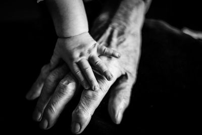 Baby holding hands with grandma's old hand. 