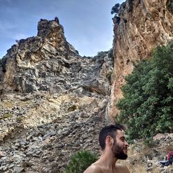 Portrait of shirtless man on rock in mountains