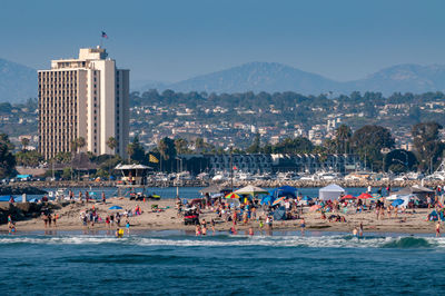 People on beach against buildings in city