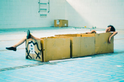 Young man sitting in box in swimming pool