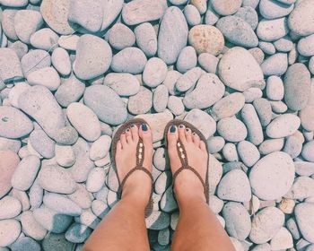 Low section of woman standing on pebbles