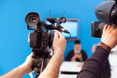 Cropped hands of male tv reporters holding television camera