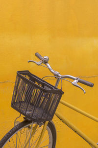 Close-up of bicycle parked against yellow wall