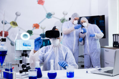 Scientist wearing virtual reality simulator colleague in background at laboratory