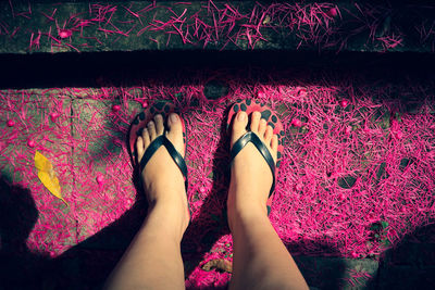 Low section of woman standing on multi colored shoes