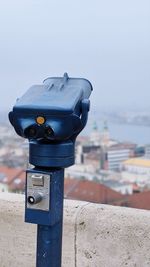 Close-up of coin-operated binoculars by sea against sky