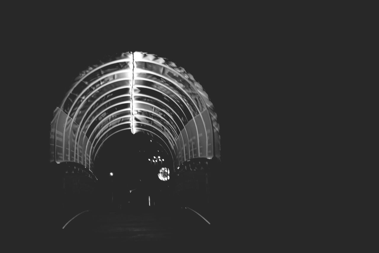 illuminated, night, built structure, architecture, arch, lighting equipment, dark, tunnel, copy space, the way forward, building exterior, clear sky, low angle view, light - natural phenomenon, indoors, no people, city, diminishing perspective, transportation, building