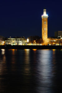 Illuminated buildings by river at night