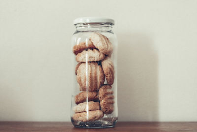 Close-up of ice cream in jar on table against wall