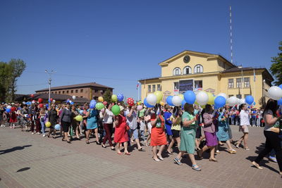 Group of people in front of building against blue sky