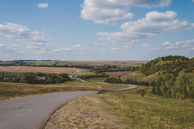 Road amidst field against sky