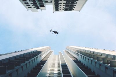 Directly below shot of helicopter flying over buildings against sky