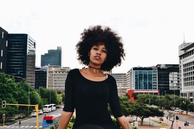 Portrait of woman in city against sky