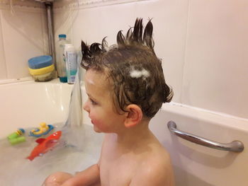 Boy looking away while sitting at bathtub