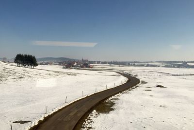 High angle view of street amidst snow covered field against sky