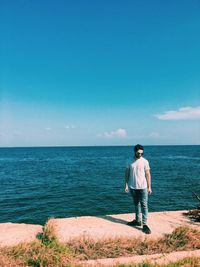 Full length of man standing against sea and sky during sunny day