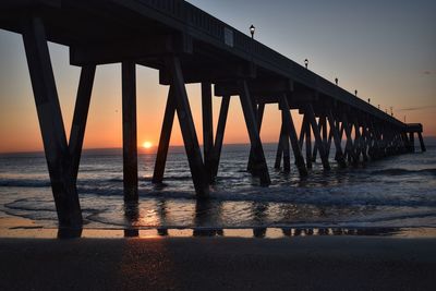 Silhouette pier on beach against sky during sunset