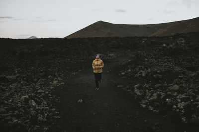 Woman running on pathway at volcanic landscape in caldera blanca volcano, lanzarote, canary islands, spain