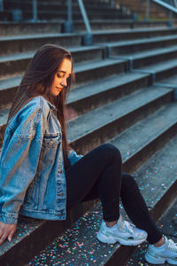 Side view of woman sitting on staircase