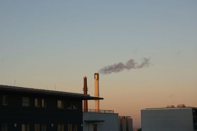 Smoke emitting from factory against sky during sunset