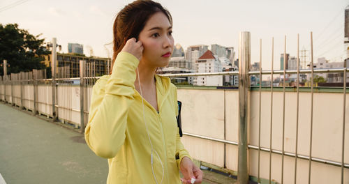 Young woman listening music while standing on road