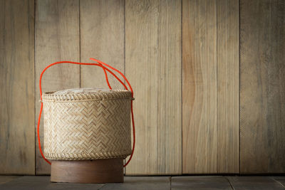 Close-up of wicker basket on hardwood floor against wall