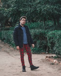 Portrait of young man standing against trees