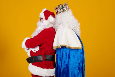 Rear view of woman holding gift against yellow background