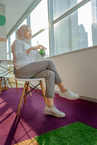 Woman sitting on chair in corridor