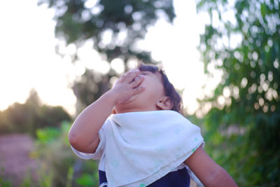 Girl covering mouth while standing on land