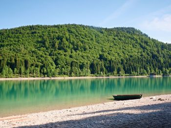 Boat anchored on bank of alps lake. mountains mirrored in smooth water level of blue lake. 