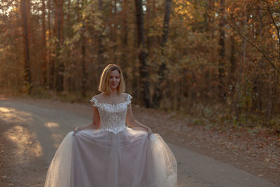 Bride standing on road against trees in forest