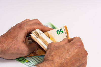 Close-up of hand holding paper against white background