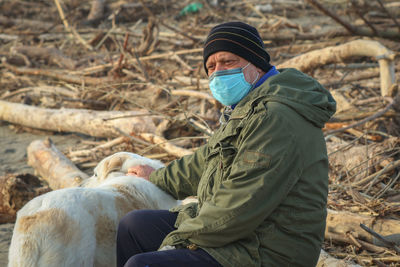 Senior man wearing mask with dog outdoors