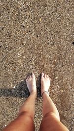 Low section of woman standing on sand