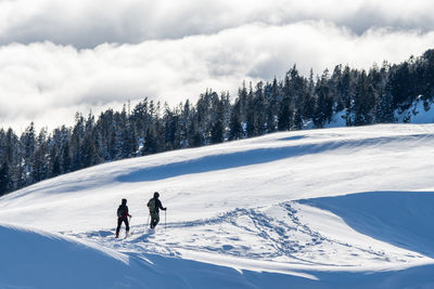 People skiing on snowcapped mountain against sky