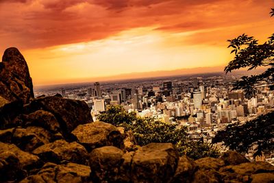 Scenic view of sea by city against orange sky