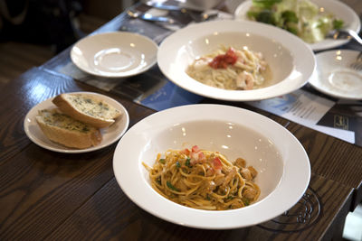 High angle view of spaghetti with garlic bread served in bowl on table