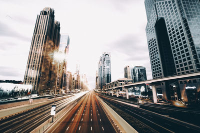 Light trails on road in city during sunset