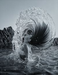 Water splashing while woman tossing her long hair in sea