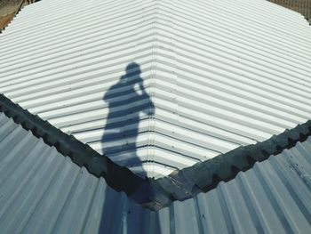 Shadow of man on railing against sky