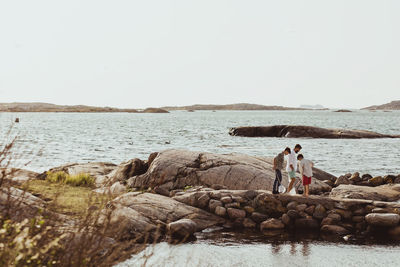 Father with sons holding fishing net while standing on rock formation